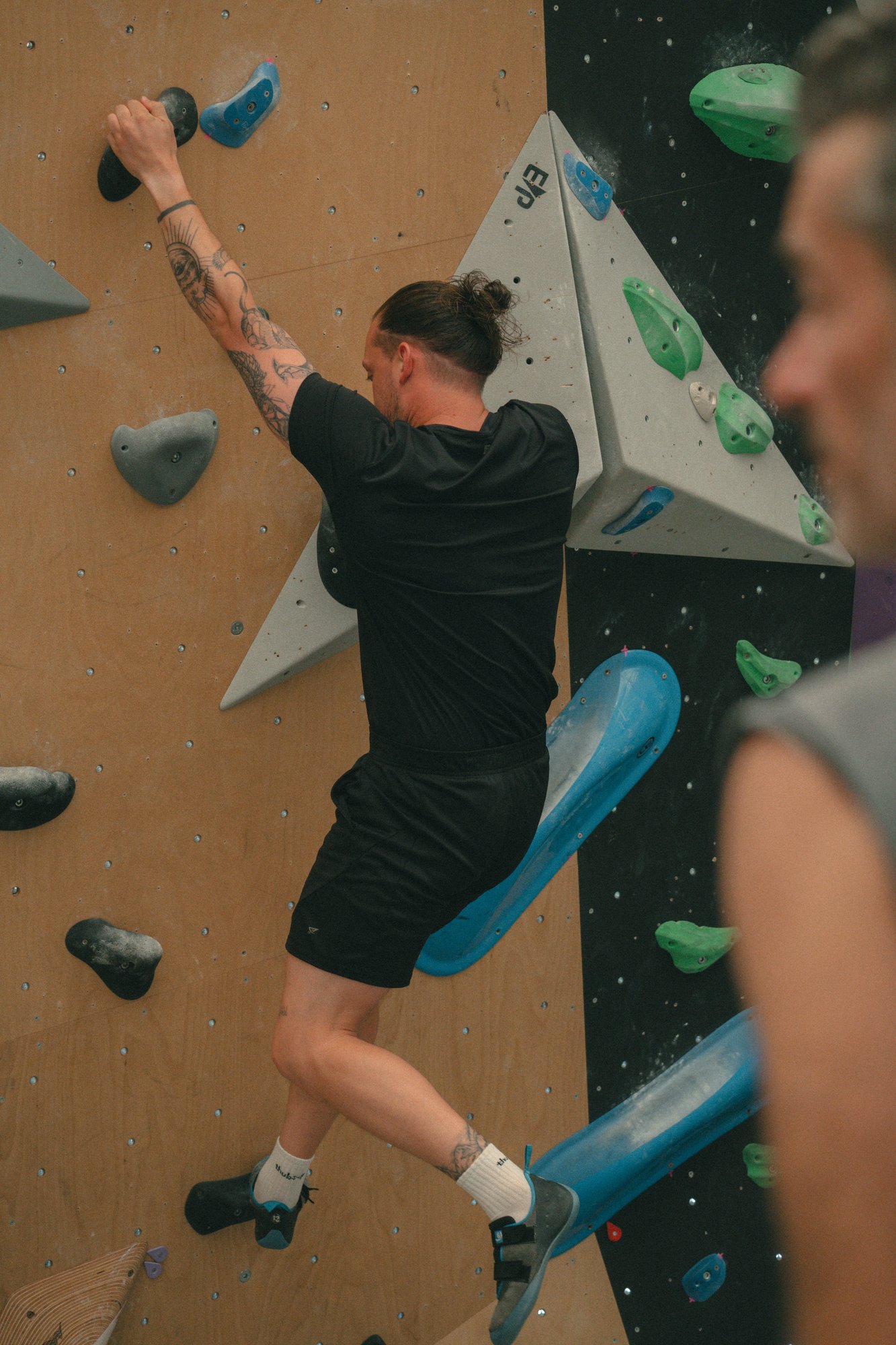 Grimpeur en mouvement sur un volume du mur de bloc
