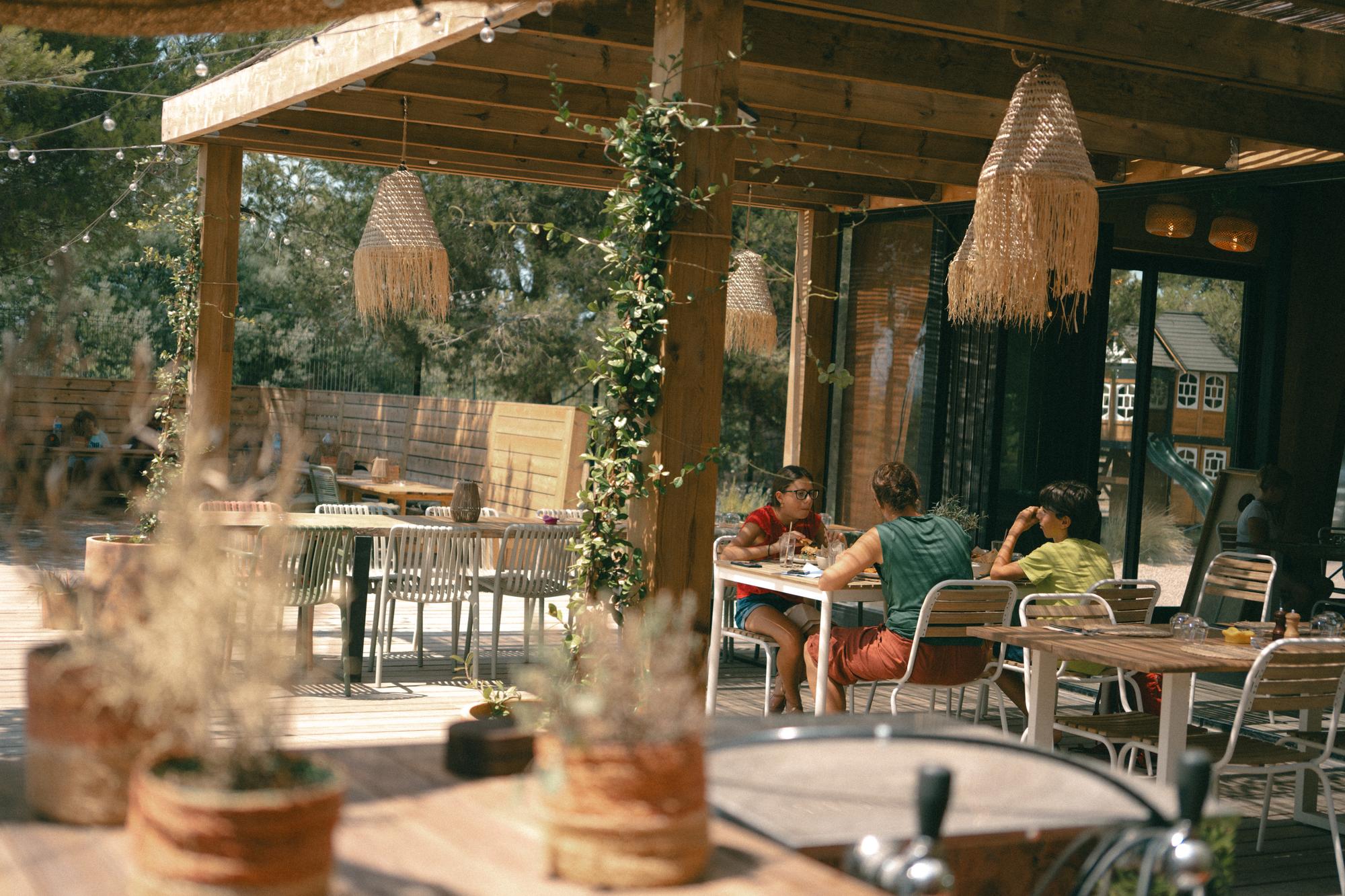 La terrasse d'ORA au soleil, ses tables sous la pergola en bois